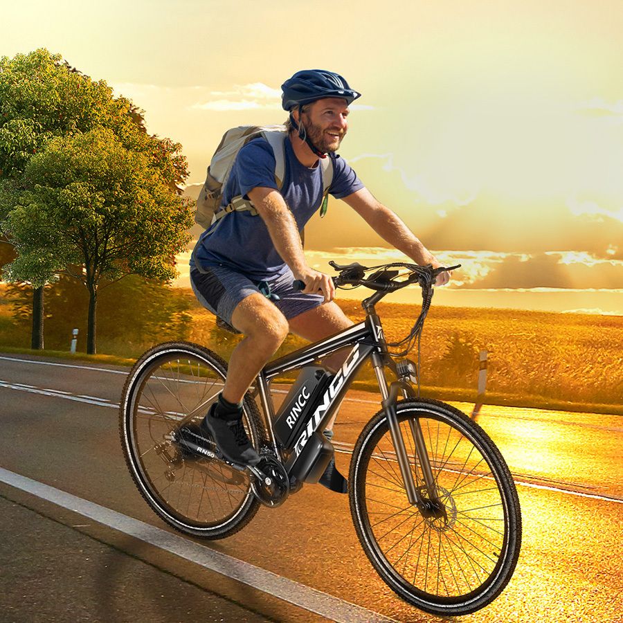 Man fietst op Rincc R200 e-bike op de weg. Draagt helm en rugzak. Landschap op de achtergrond.