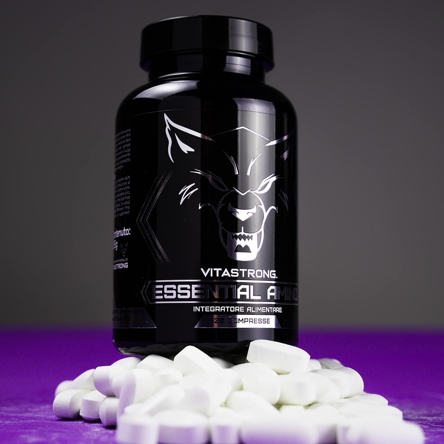 Flacon noir Vitastrong Essential Amino, comprimés en dessous. Inscription et logo loup. Fond violet.