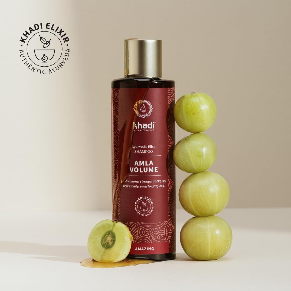 Bruine fles met productnaam en logo. Tekst: Amla Volume. Groene vruchten ernaast. Logo: Khadi Elixir.