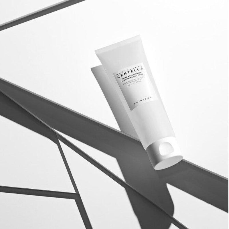 Tube blanc, ombre. Texte: MADAGASCAR CENTELLA, Tone Brightening Cleansing Gel Foam. Marque SKIN1004.