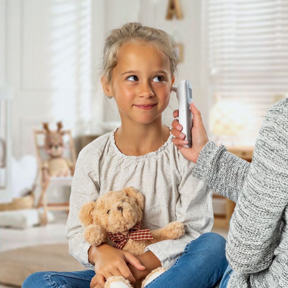 Enfant avec thermomètre auriculaire. Thermomètre à l'oreille. Marque : reer.