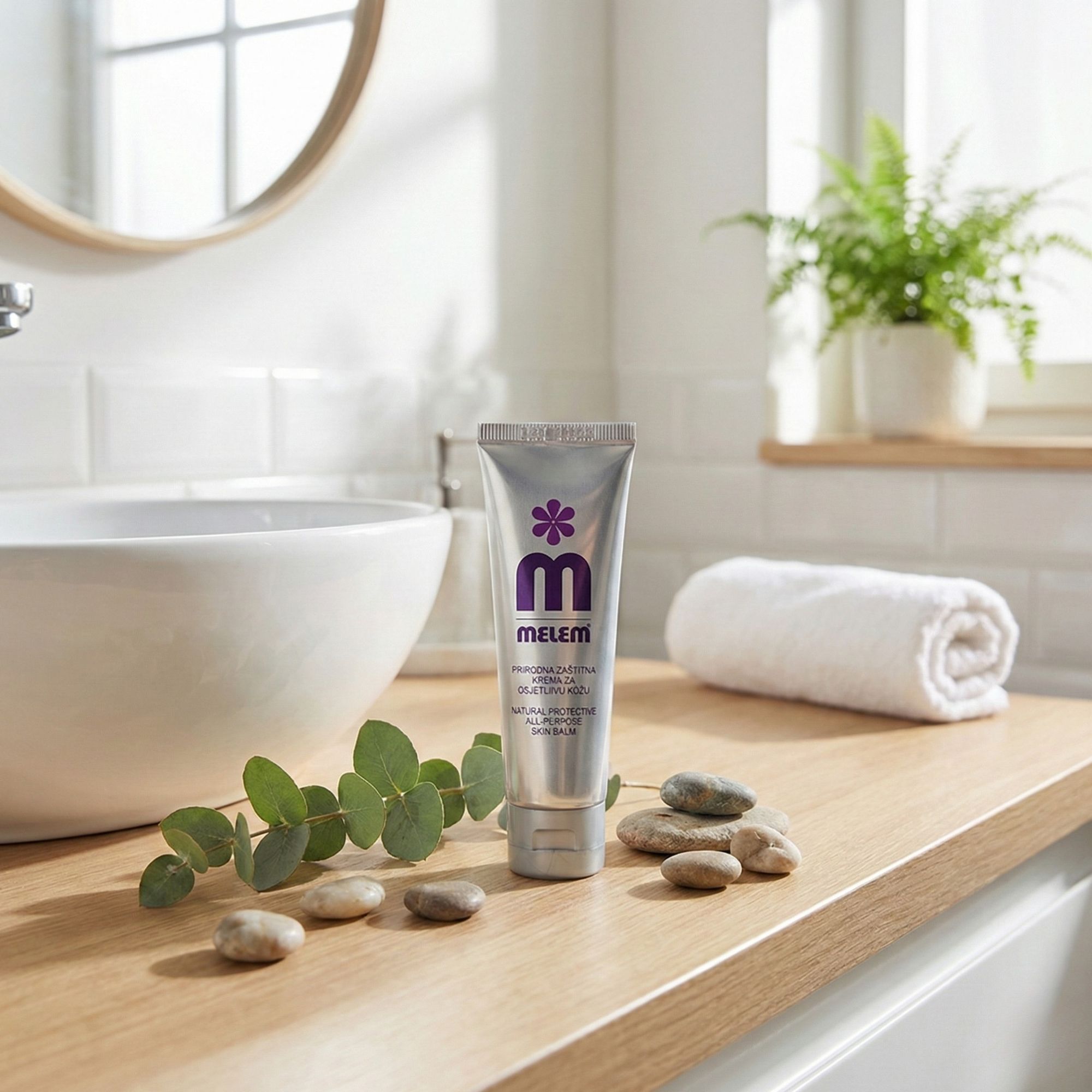 Tube argenté avec logo violet et texte MELEM sur une surface en bois. Décoration : pierres, branche, serviette.