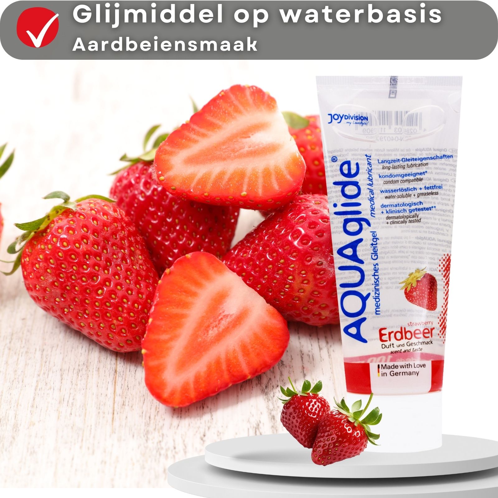 Tube glijmiddel AQUAglide aardbei. Op waterbasis, aardbeiensmaak. Aardbeien op houten ondergrond.