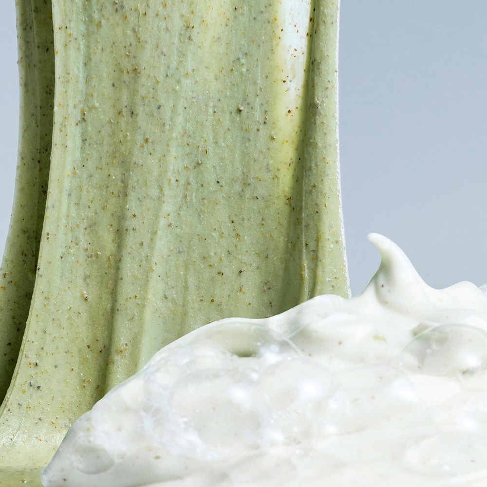 Gros plan sur une substance verte gélifiée et une mousse blanche. La substance verte contient des particules sombres.