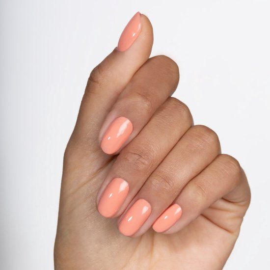 Main avec ongles vernis couleur pêche. Tous les ongles sont vernis.