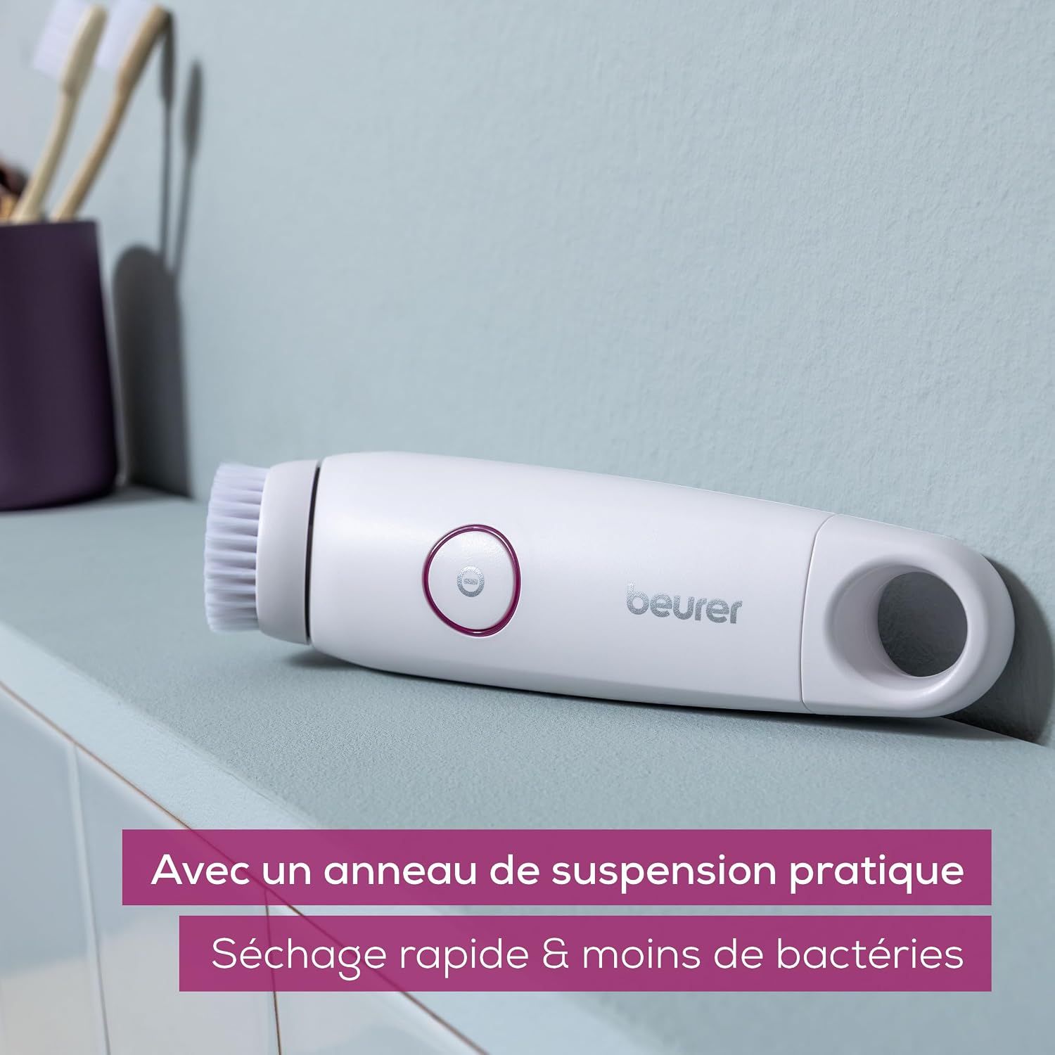 Brosse nettoyante pour le visage blanche avec un anneau et un bouton roses.