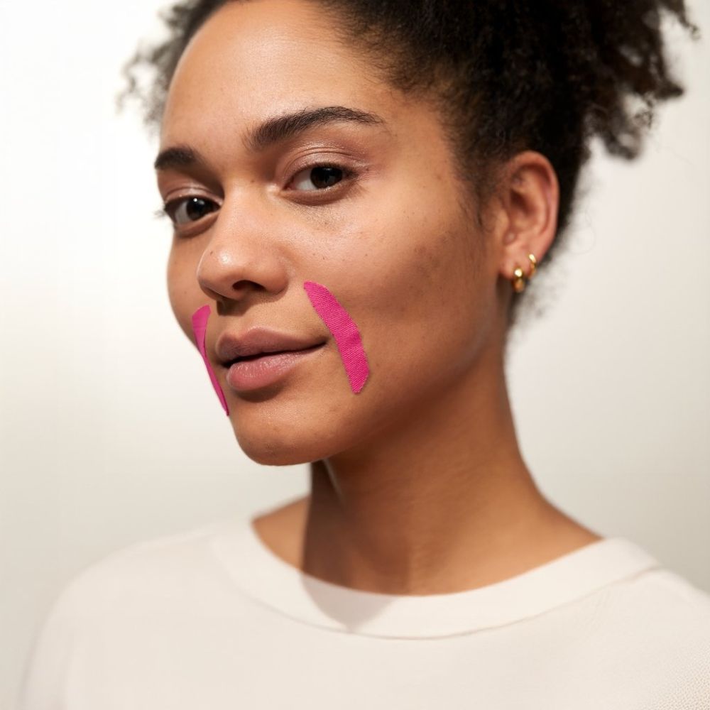 Femme avec patchs roses sur la bouche. Patchs aux coins de la bouche. Teint clair. Environnement clair.