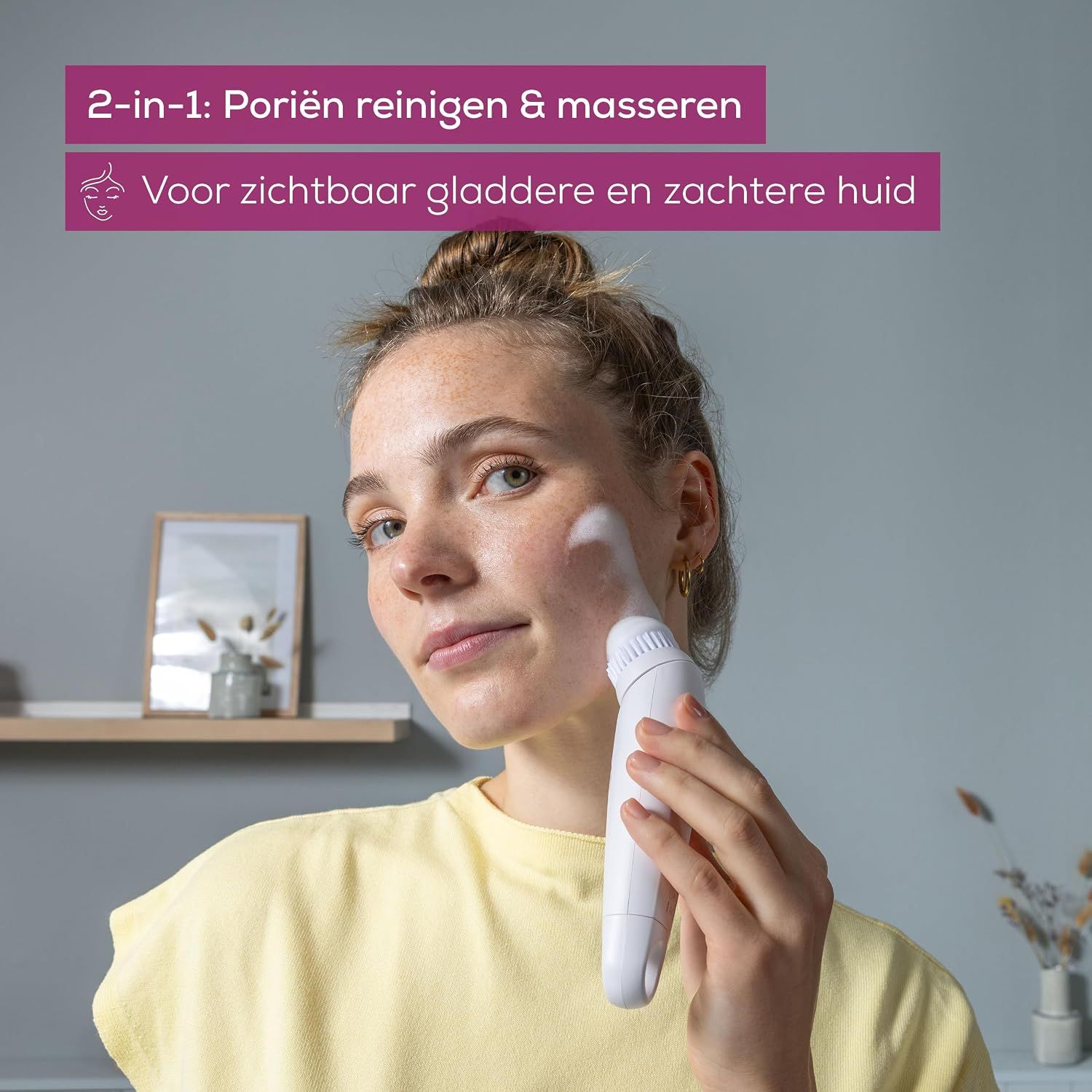 Vrouw met sproeten reinigt haar gezicht met een witte borstel en schuim.