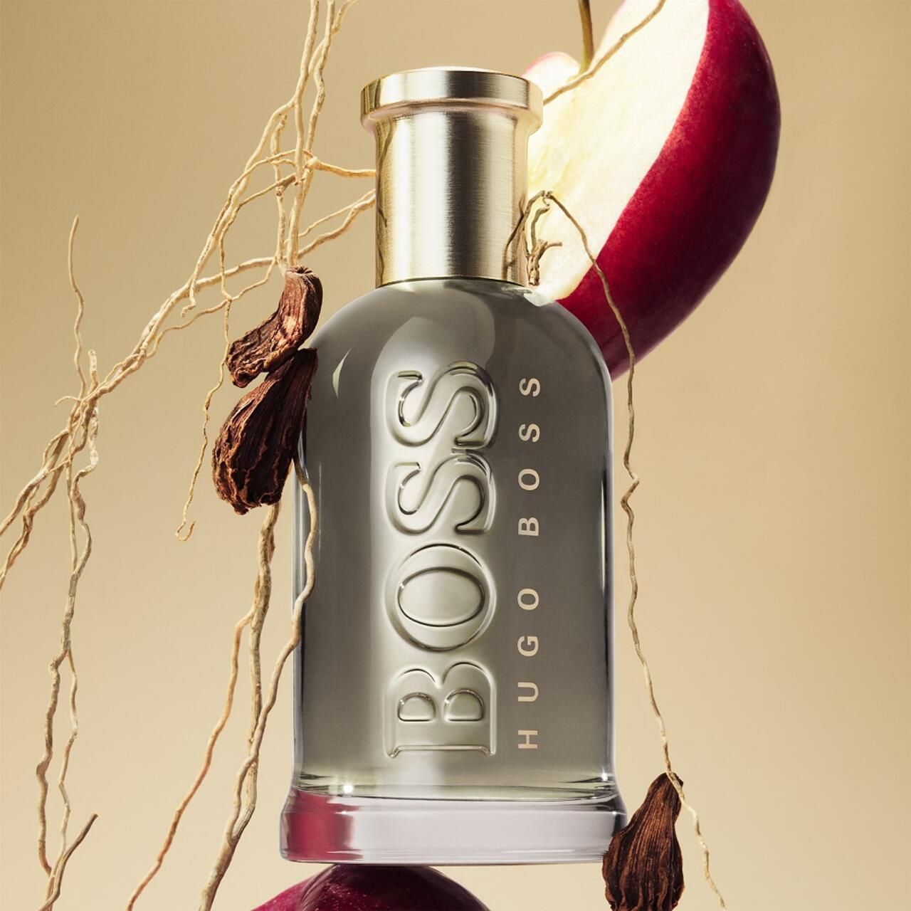 Boss Bottled Eau de Parfum fles met gouden dop. Omringd door appels, kruiden en takken.