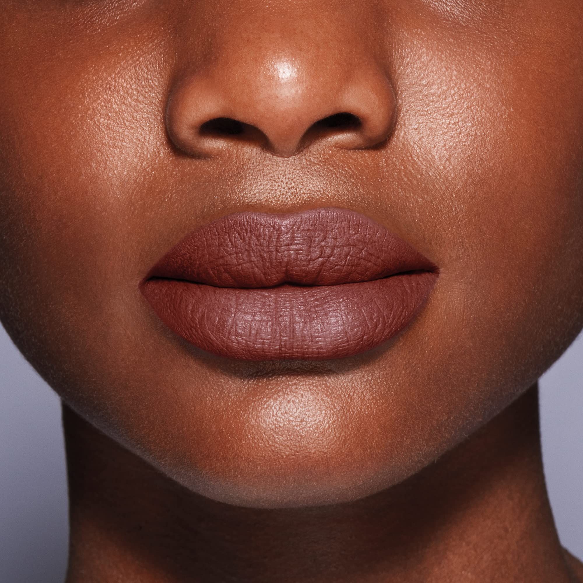 Close-up van lippen, bedekt met bruine lipstick. Huidskleur donker.