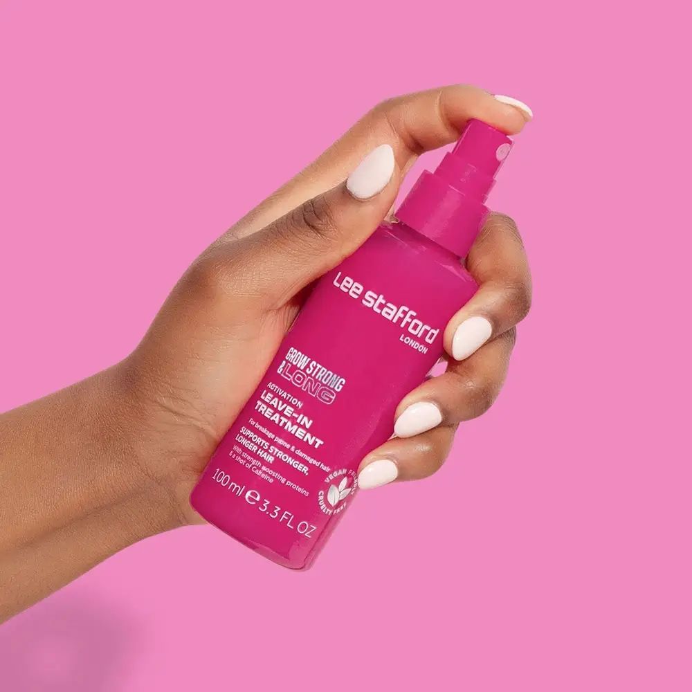 Roze sprayfles in een hand. Productnaam en tekst zichtbaar.