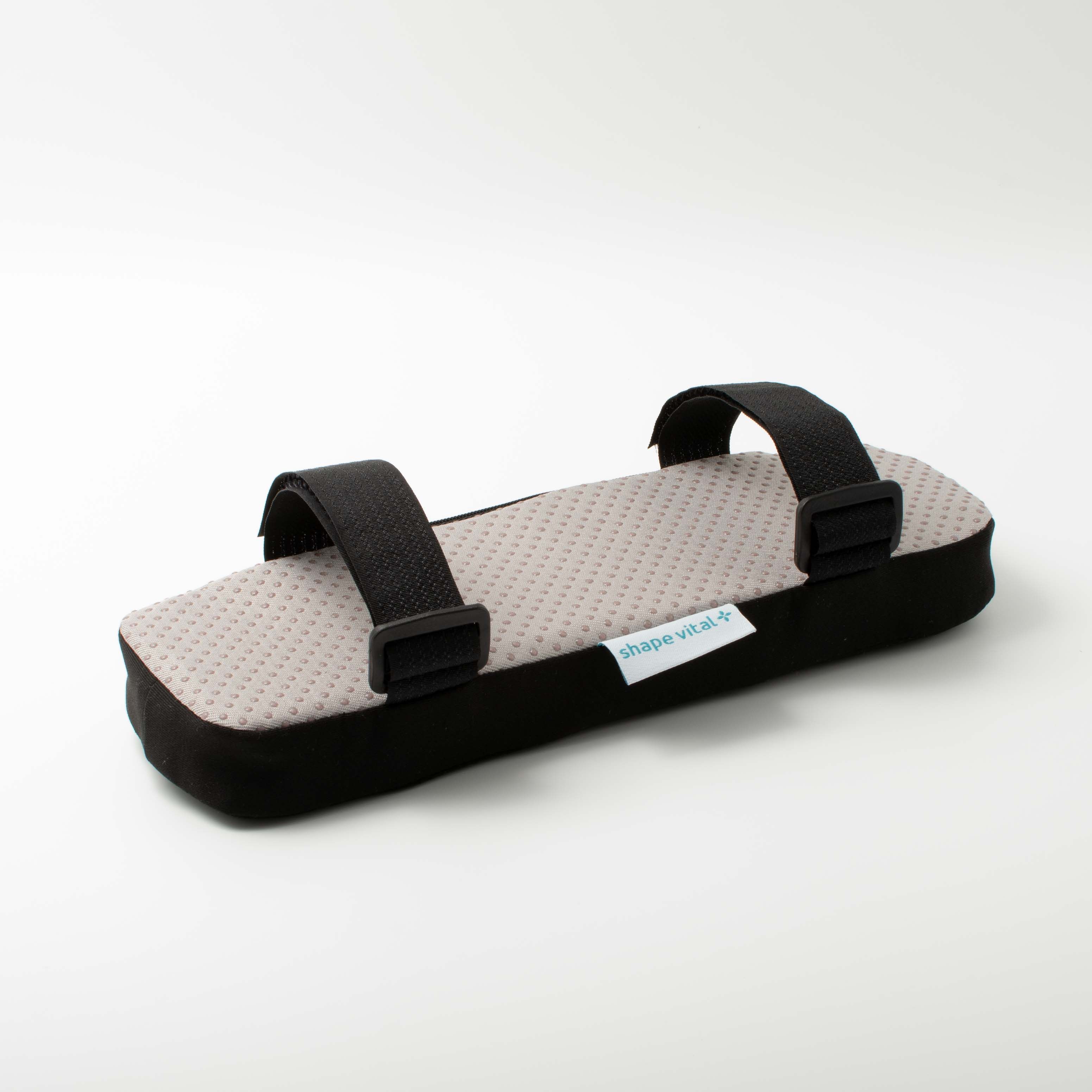 Armleuningkussen met grijs, noppen oppervlak en zwarte rand. Zwarte riemen met clips. Label 'shape vital+'.