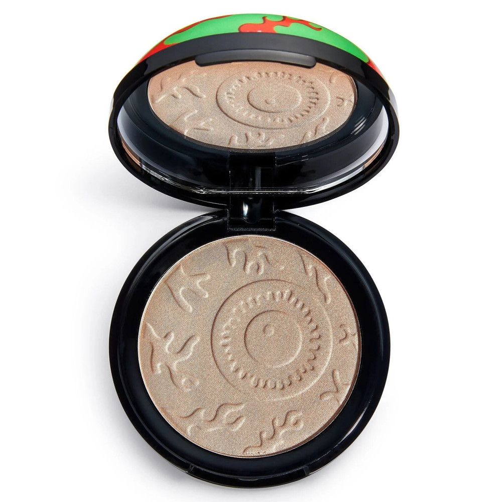 Highlighter rond avec miroir. Poudre beige avec motif en relief. Boîtier noir avec couvercle vert, design rouge et noir.