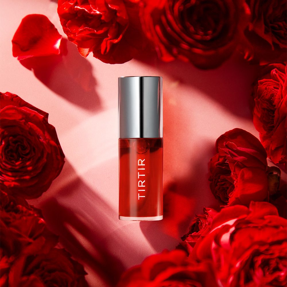 TIR TIR My Glow Lip Oil Rosy entouré de roses rouges.