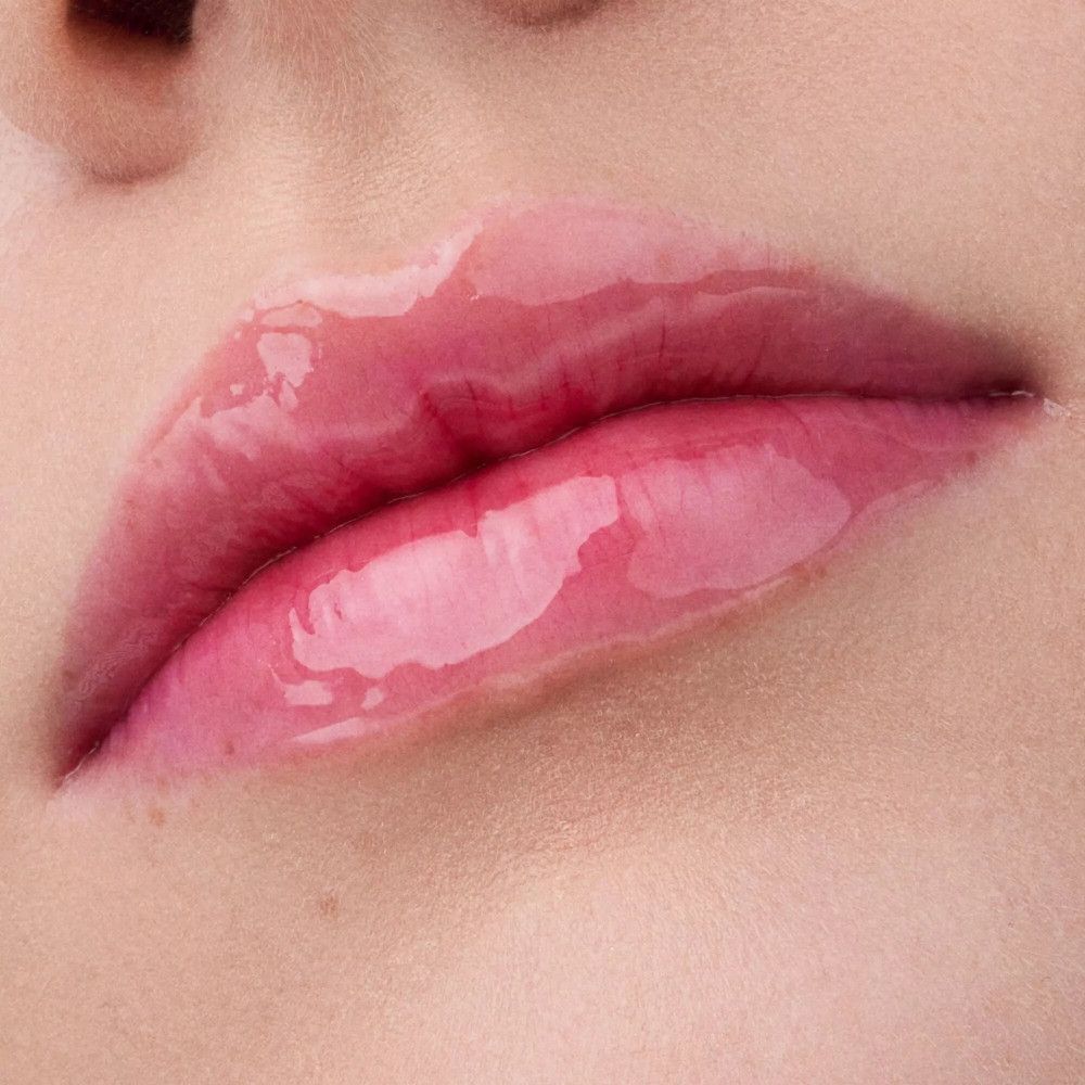 Close-up van glanzende, roze lippen. Lipolie-effect.