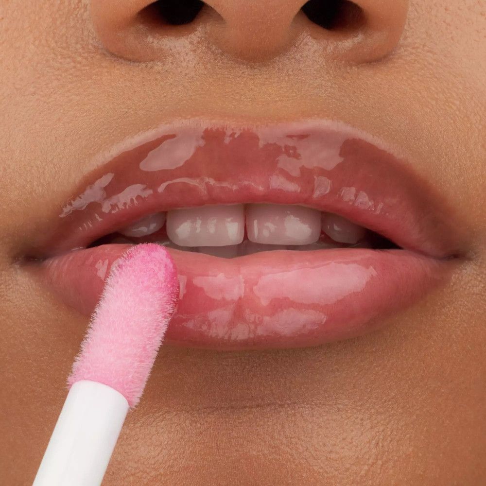 Close-up van lippen met een applicator. Glanzende lipolie, roze applicator.