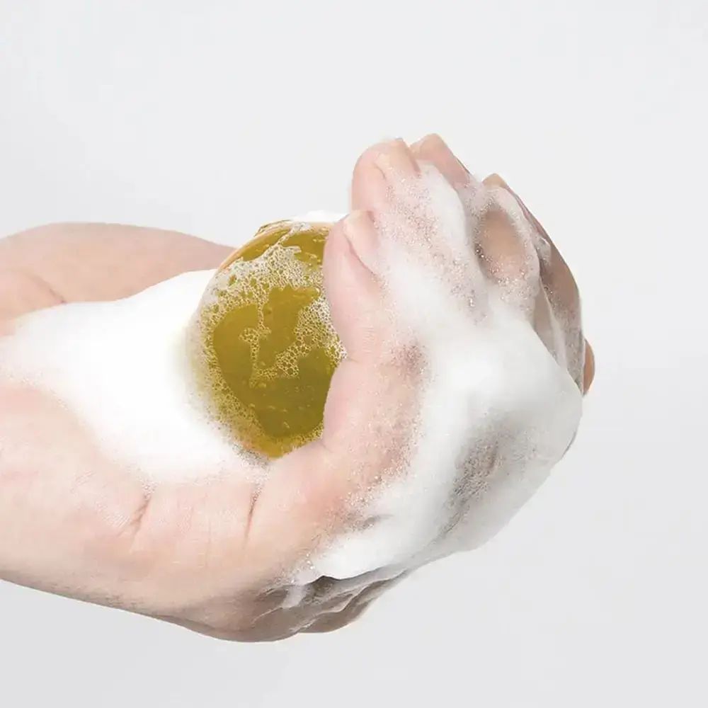 Hand die een gele bal met schuim vasthoudt. Close-up.