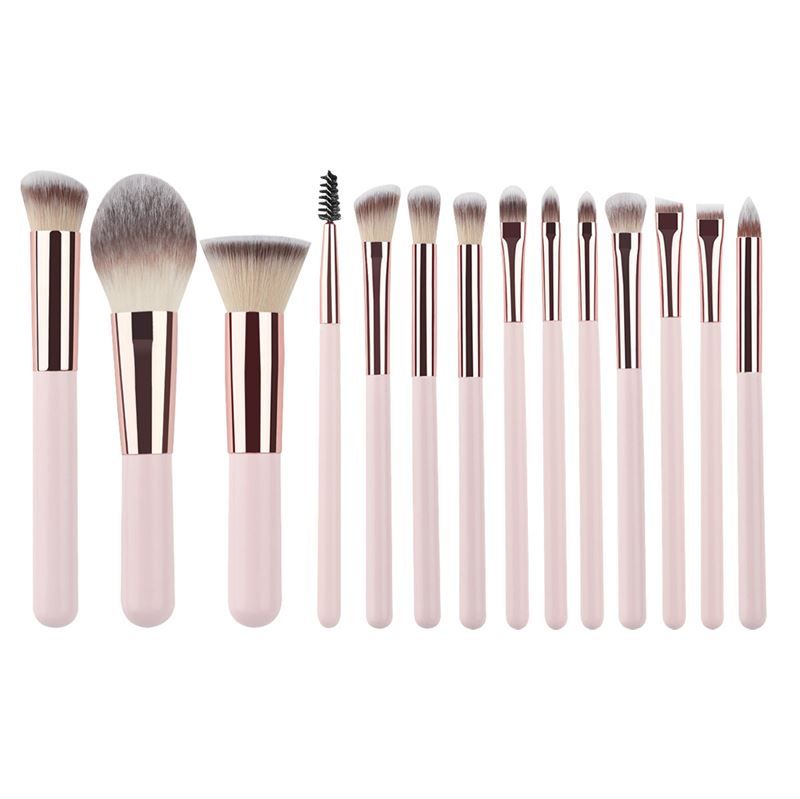 Ensemble de pinceaux de maquillage. Manches roses, viroles dorées, différentes têtes. Sur fond blanc.