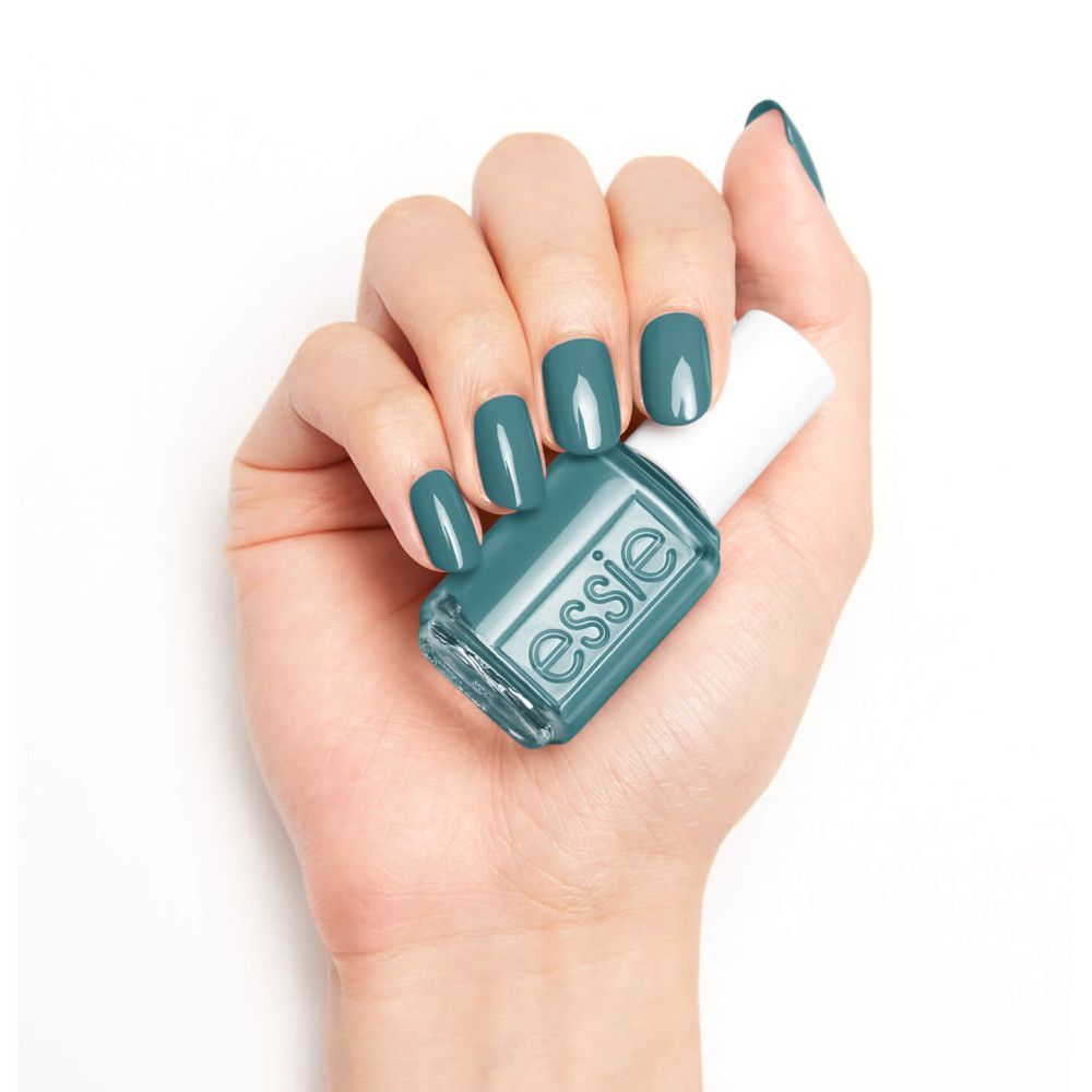 Hand met gelakte nagels en nagellakflesje. Flesje met witte dop, opschrift "essie". Turquoise nagellak.