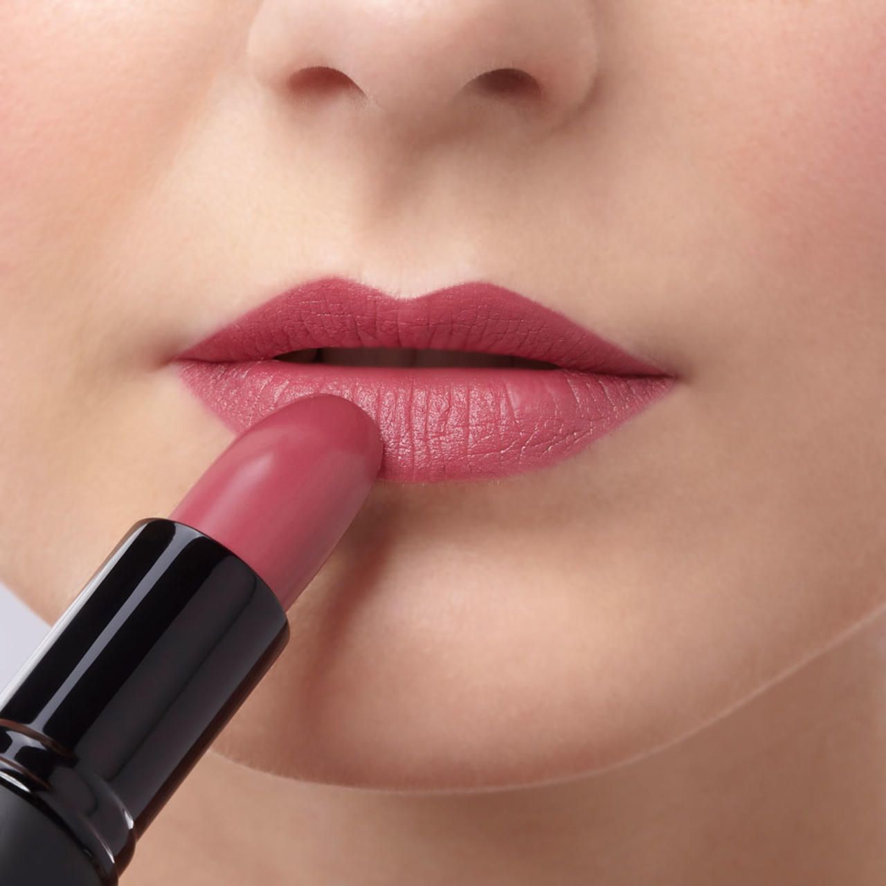 Roze lipstick wordt op lippen aangebracht. Close-up.