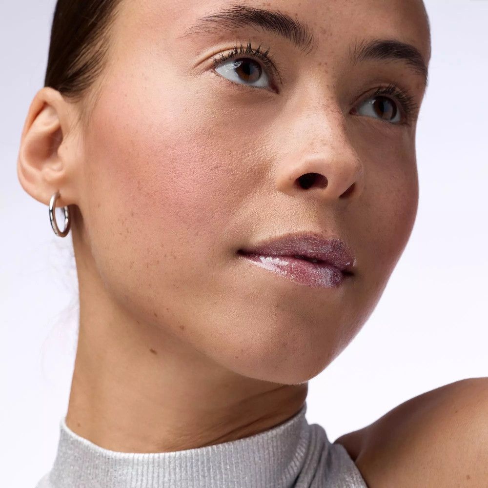 Vrouw met lipgloss. Lichte huid, zilveren coltrui. Glanzende lippen.