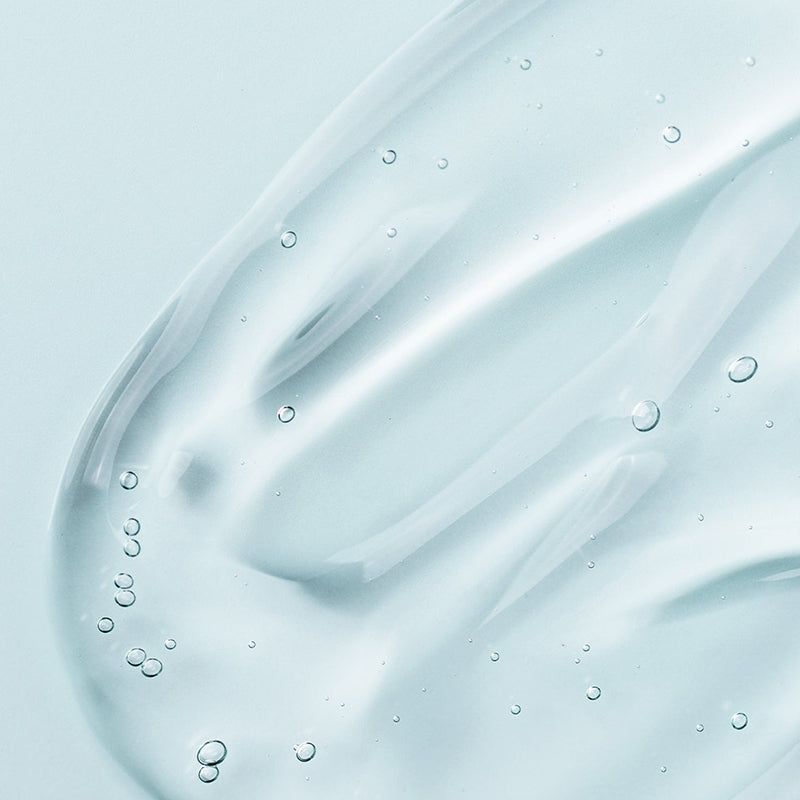 Close-up van een transparante vloeistof met bellen. Geen fles zichtbaar.