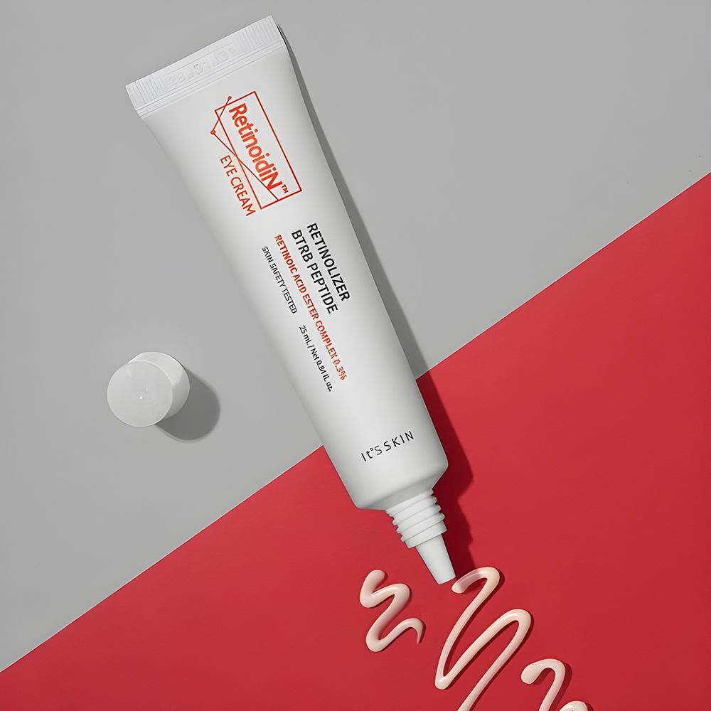 Witte tube met oranje logo en tekst. Productnaam: Retinoidin Eye Cream. Crèmekleurige streep op rode achtergrond.