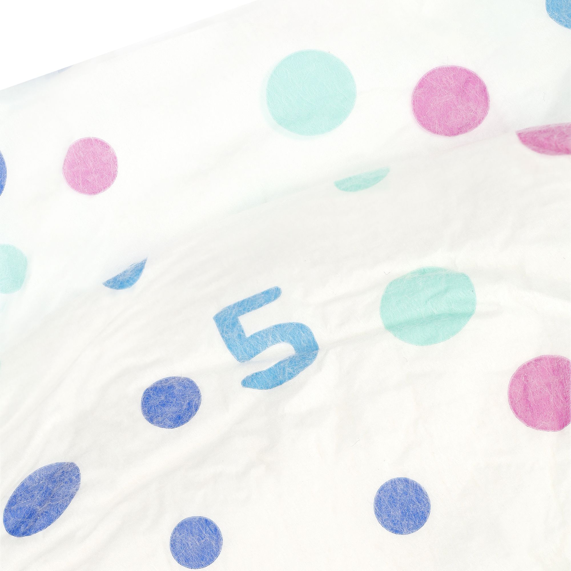 Close-up van een witte luier met gekleurde stippen en het cijfer 5 in blauw.