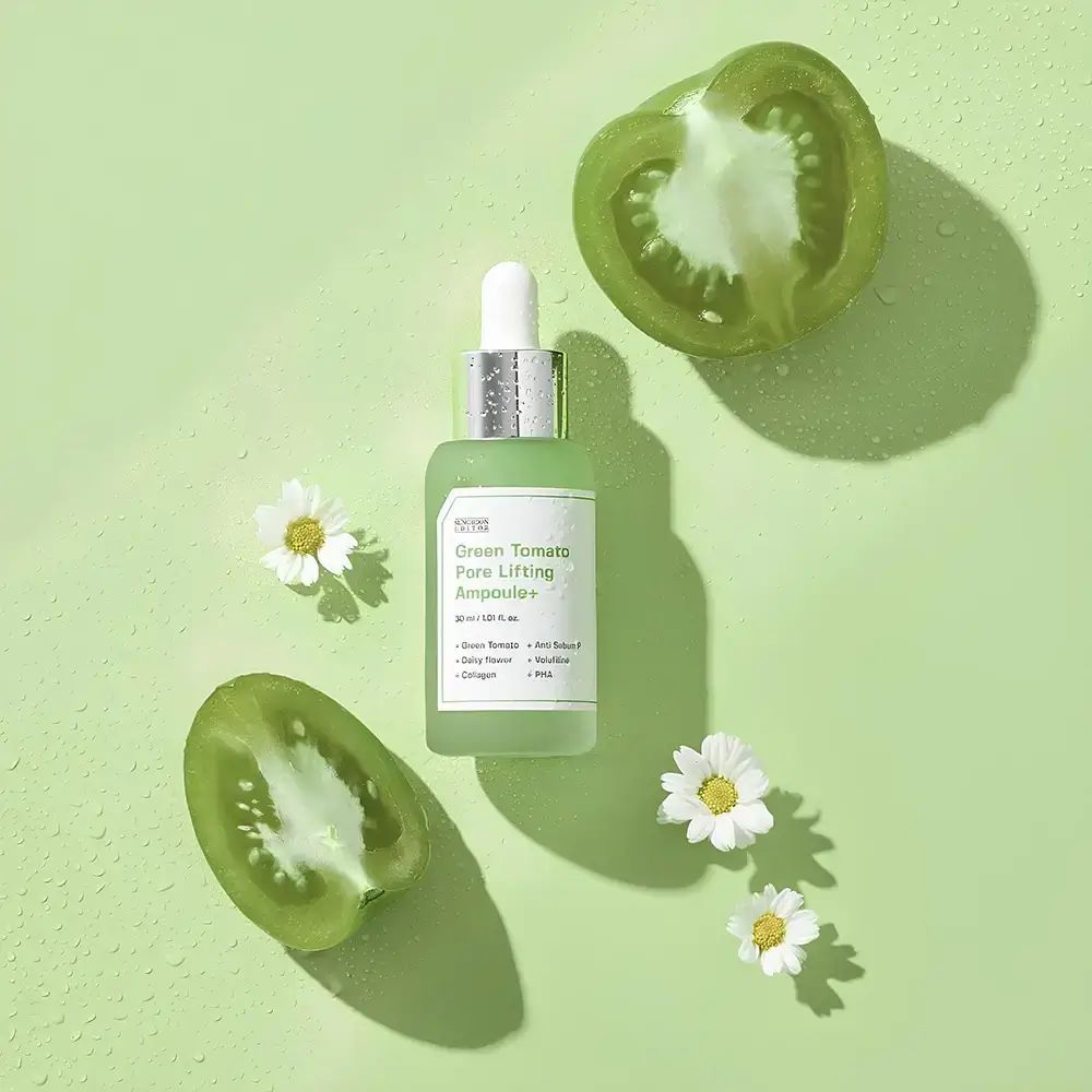 Groen serumflesje, groene tomatenhelften en madeliefjes op groene achtergrond.