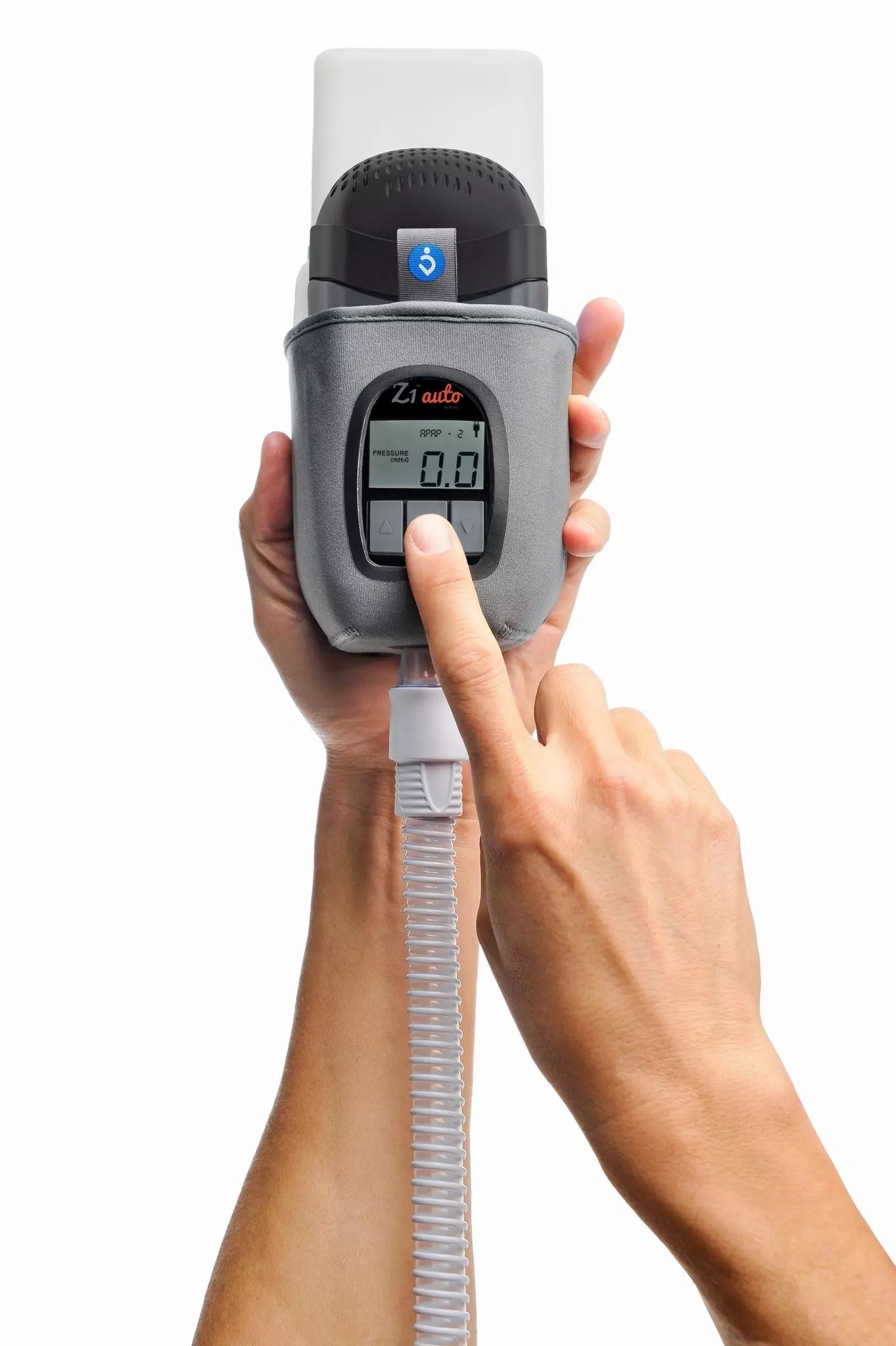 Appareil CPAP de voyage gris avec écran et tuyaux, tenu par des mains.