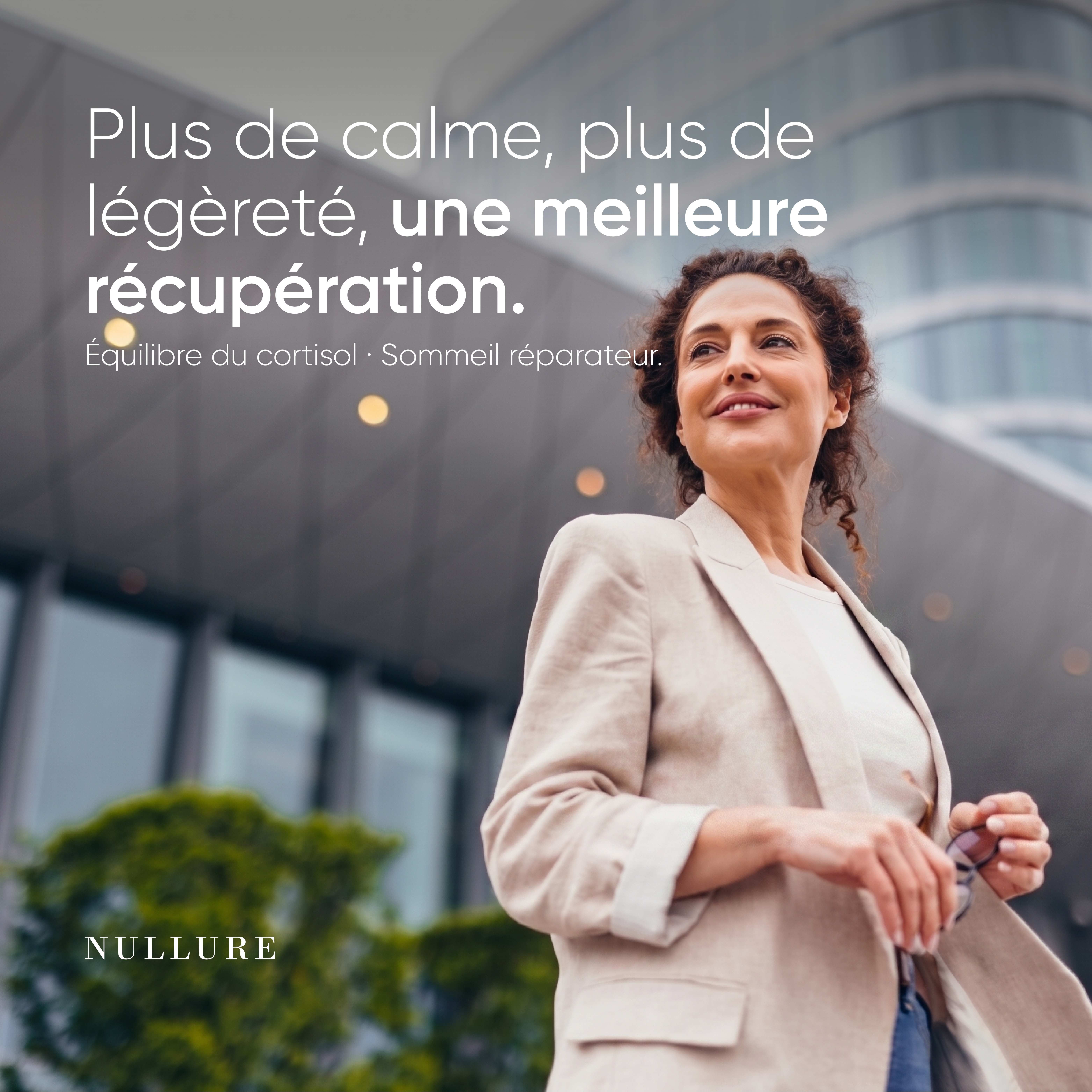 Femme en blazer beige regardant vers le haut, avec un texte sur le calme, la légèreté et la récupération. Marque : NULLURE.