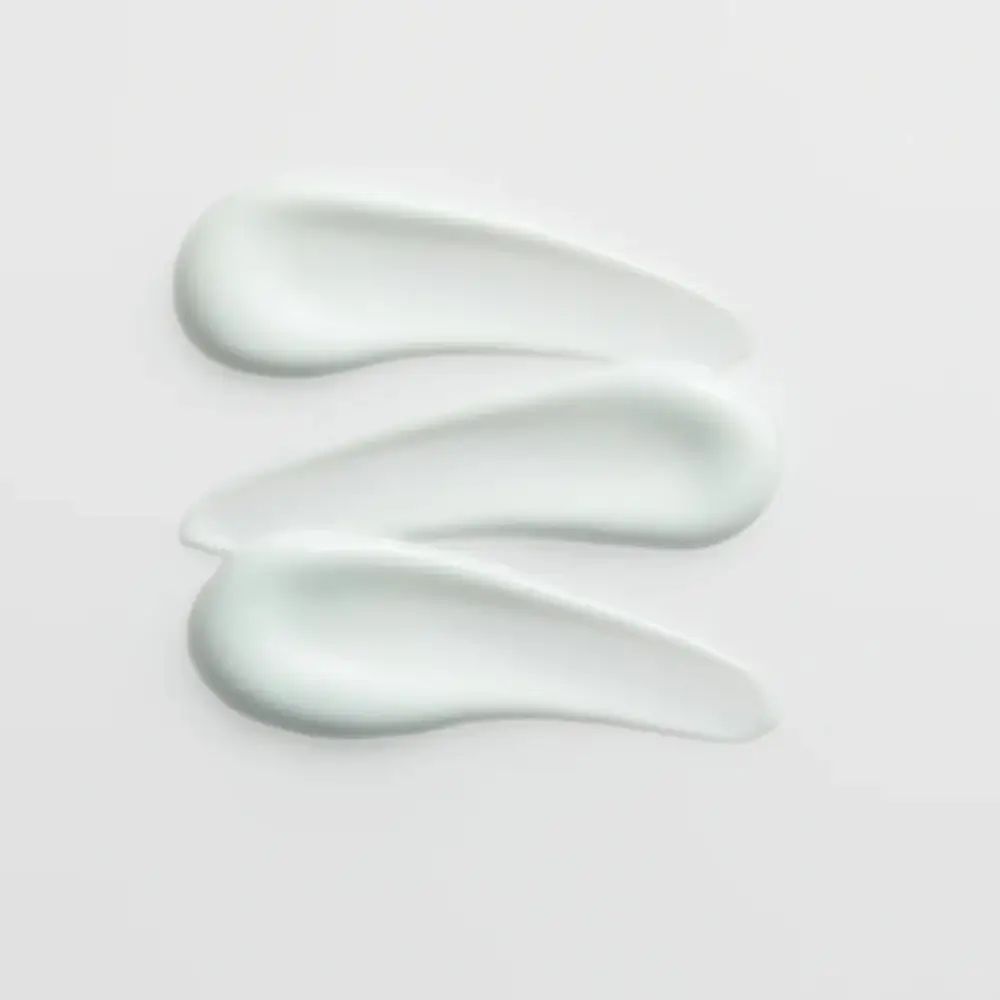 Trois traits de crème sur fond clair. Texture de la crème visible.