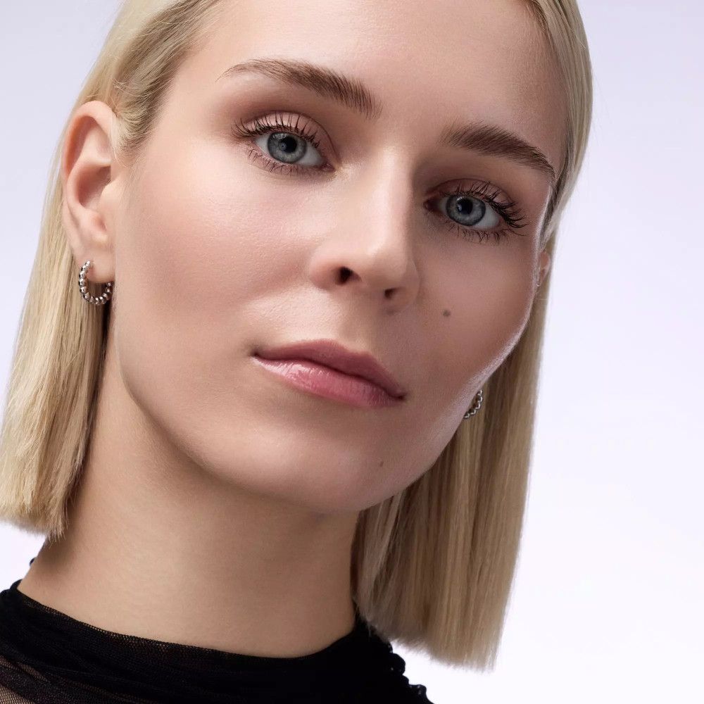 Gros plan d'une femme blonde. Yeux bleus, masque à lèvres. Haut noir.