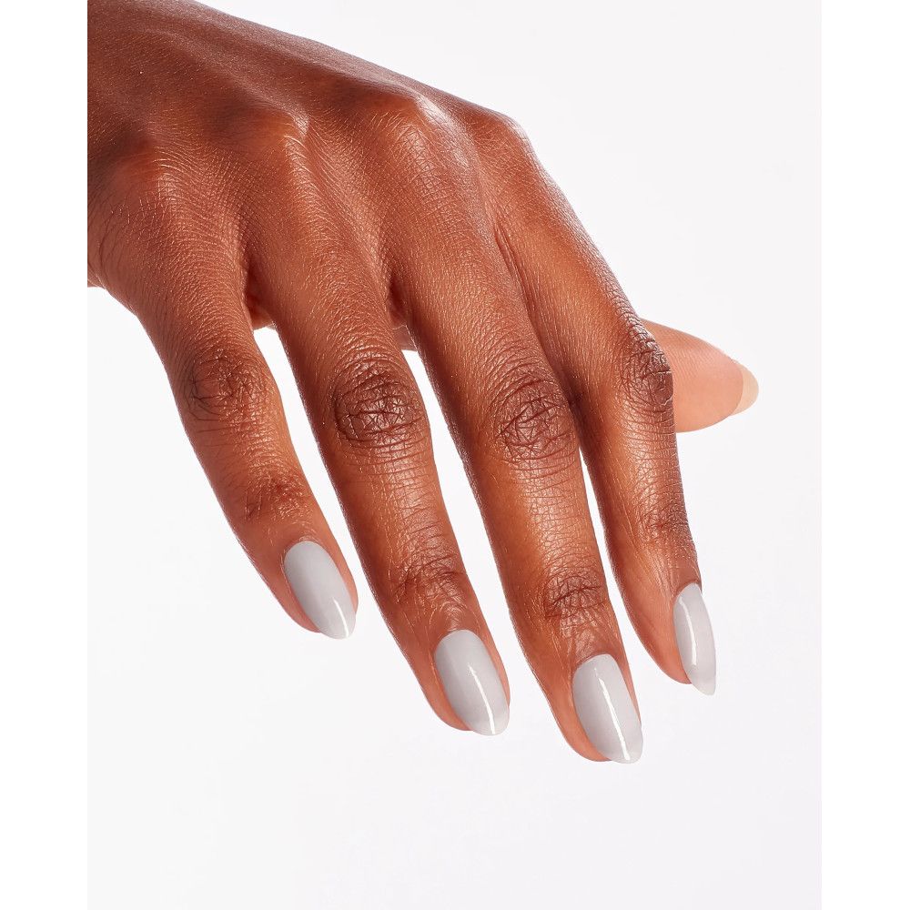 Main avec ongles vernis. Les ongles sont peints en gris clair. Le fond est blanc.