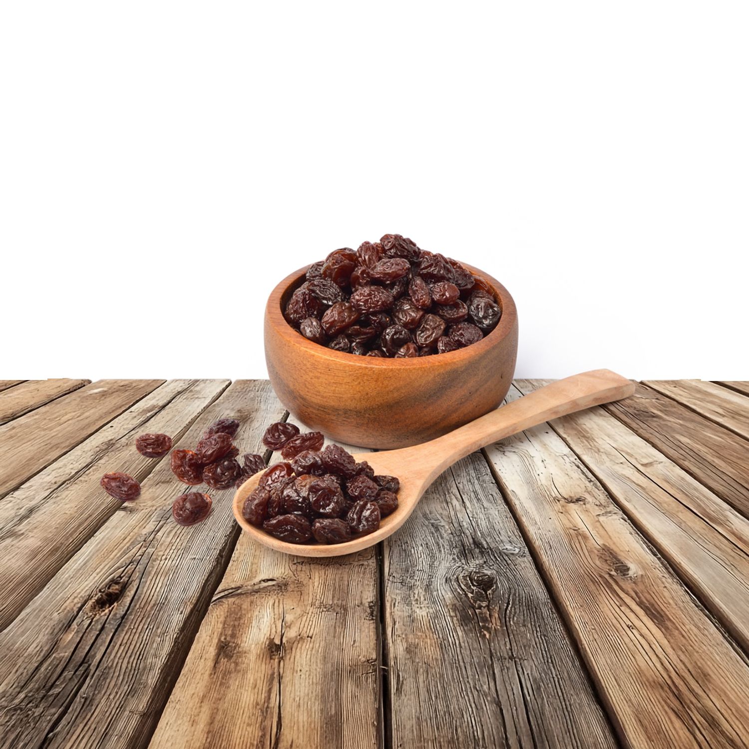 Raisins noirs dans un bol et une cuillère en bois.