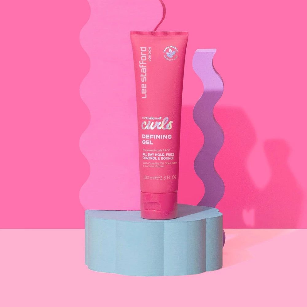 Tube rose Lee Stafford For The Love Of Curls Defining Gel sur un socle bleu, fond rose.