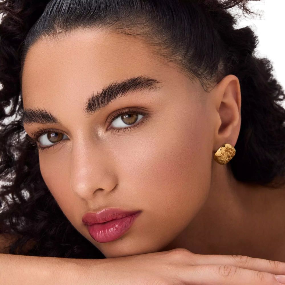 Portret van een vrouw met bruine ogen en lippenstift. Gouden oorbellen. Donker haar.