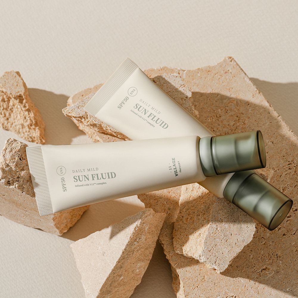 Twee tubes op stenen. Opschrift: SPF50, Daily Mild Sun Fluid, UVA. Merk: Village 11 Factory.