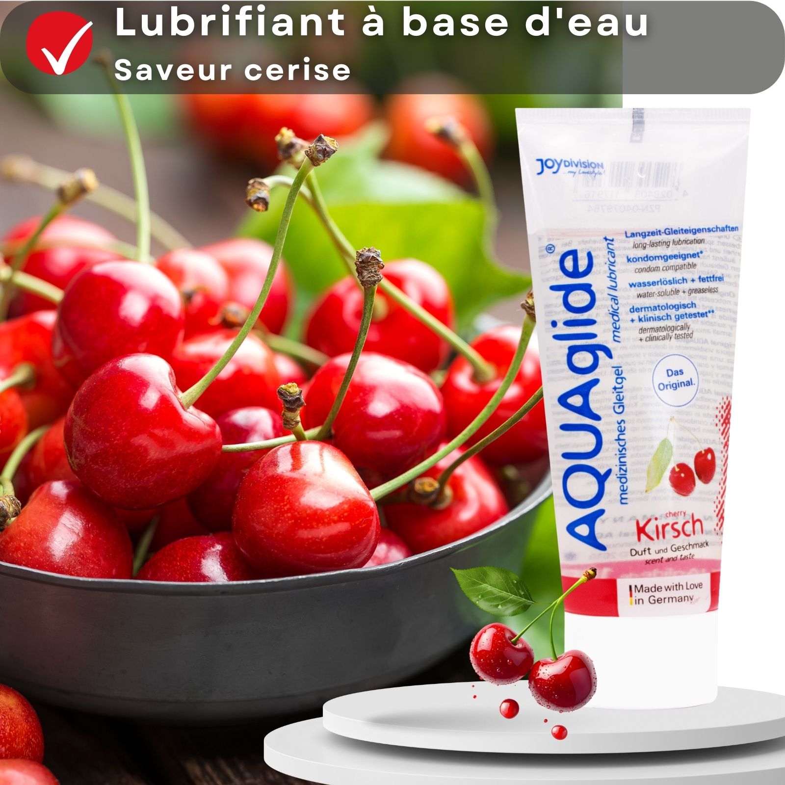 Tube de produit AQUAglide, Kirsch, à côté de cerises dans un bol. Cerises sur un piédestal blanc.