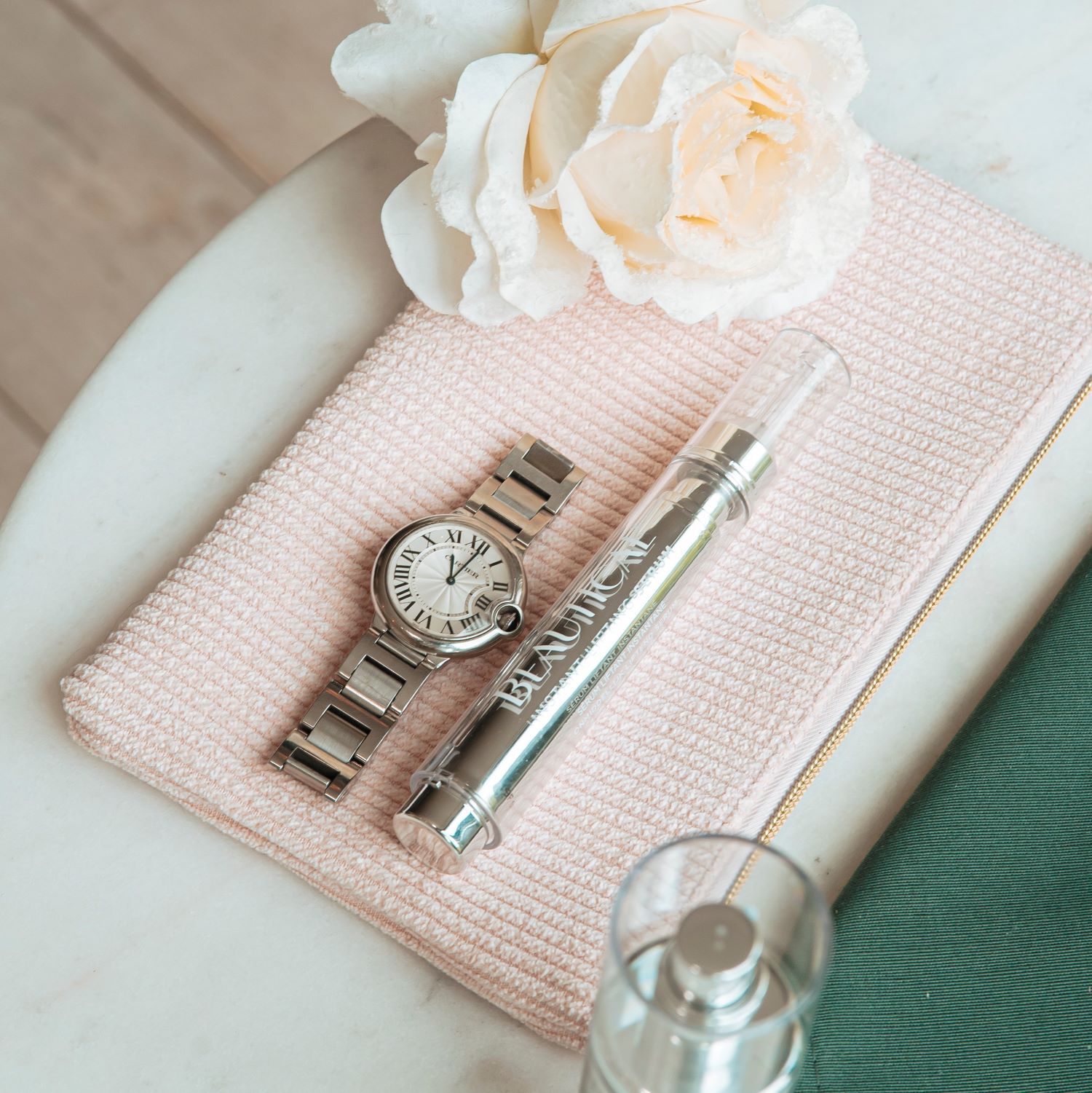 BEAUTICAL Instant Lifting Serum. Horloge, roze doek. Op een witte tafel.