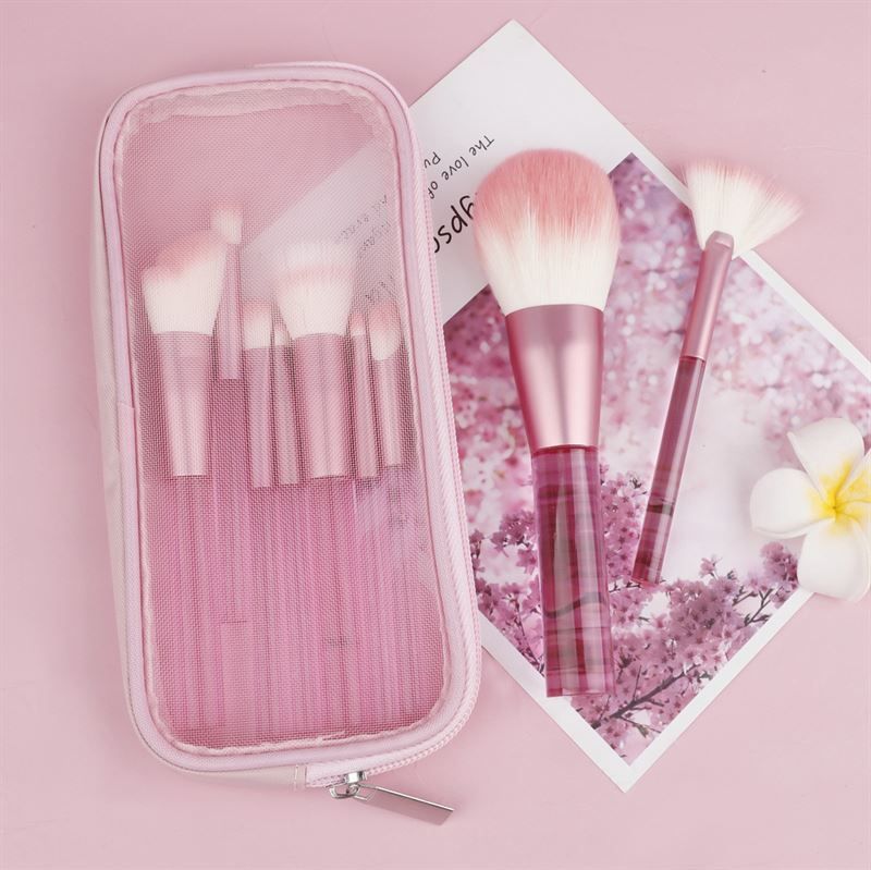 Ensemble de pinceaux de maquillage roses avec étui. Pinceaux avec manches transparents et poils roses. Sur fond rose.