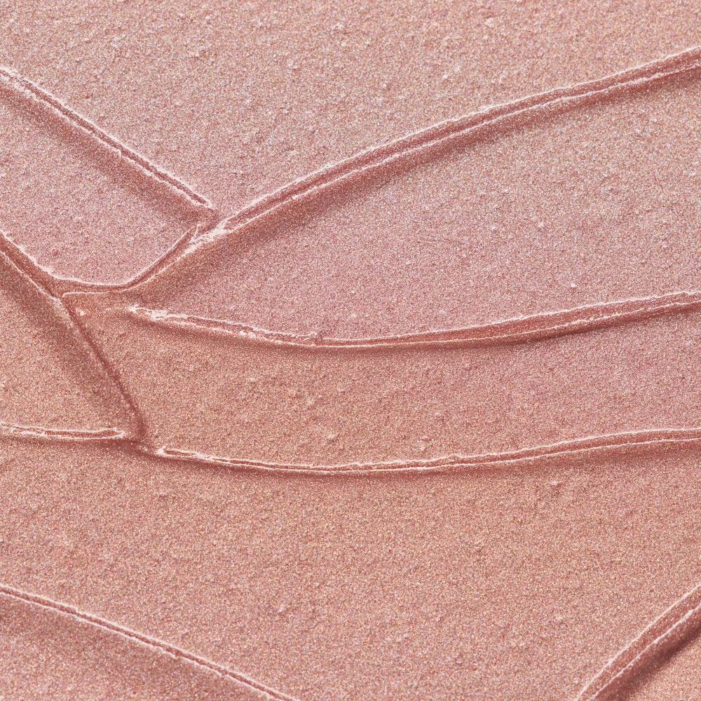 Gros plan sur la texture du stick highlighter rose avec effet scintillant.
