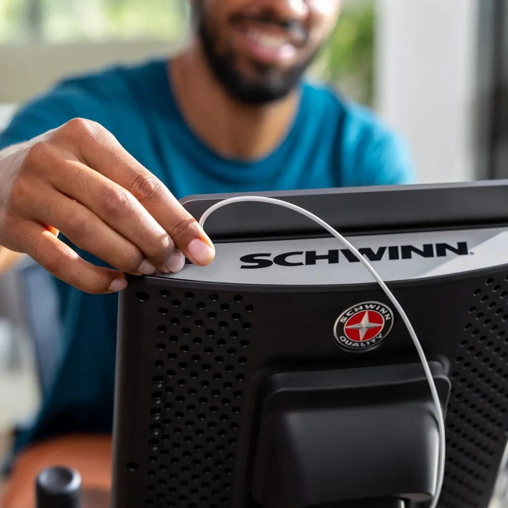 Gros plan sur l'écran d'un vélo d'exercice. Marque : Schwinn. Connexion par câble.