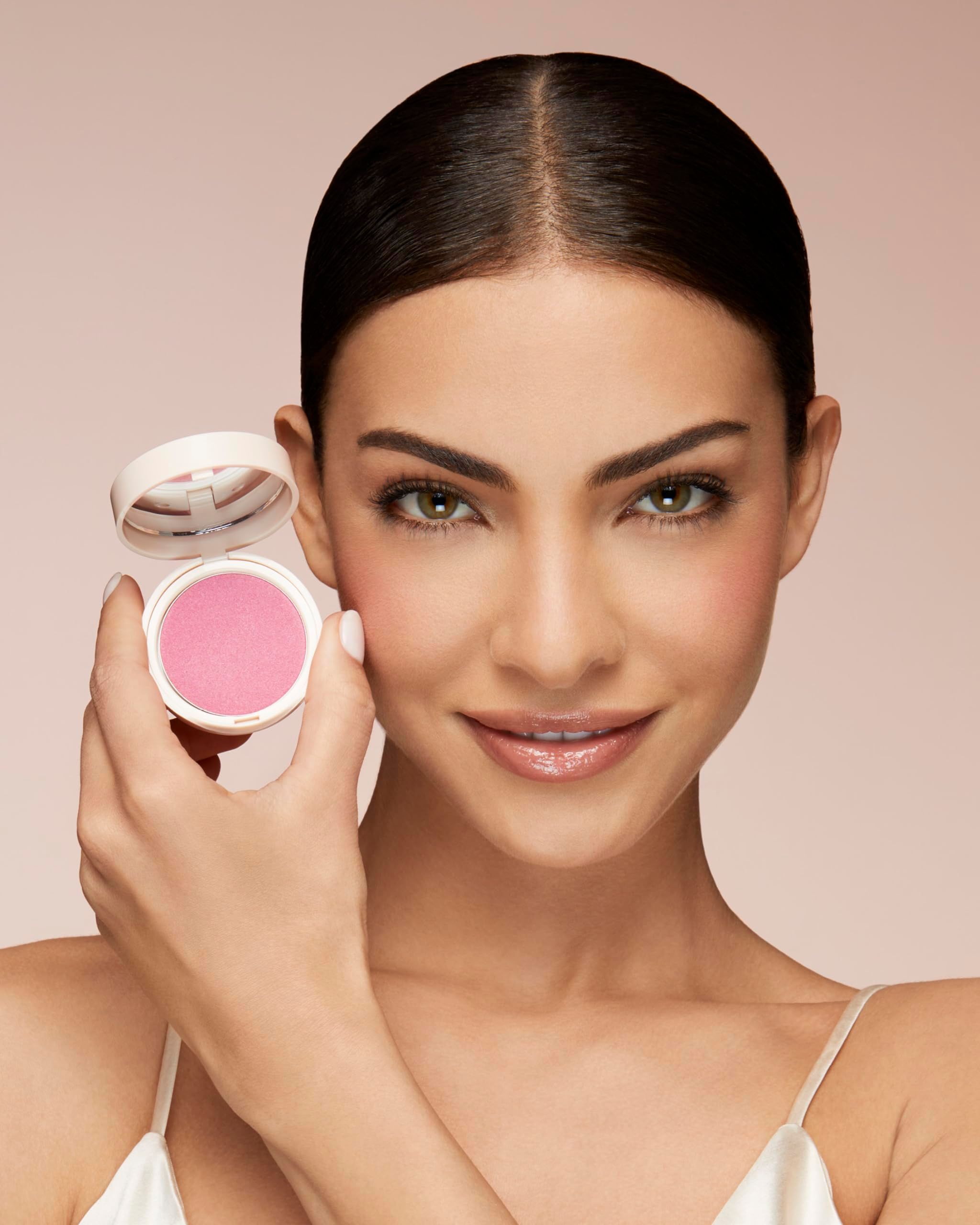 Vrouw houdt blush-container vast. Roze poeder in de container. Vrouw met blush op wangen.