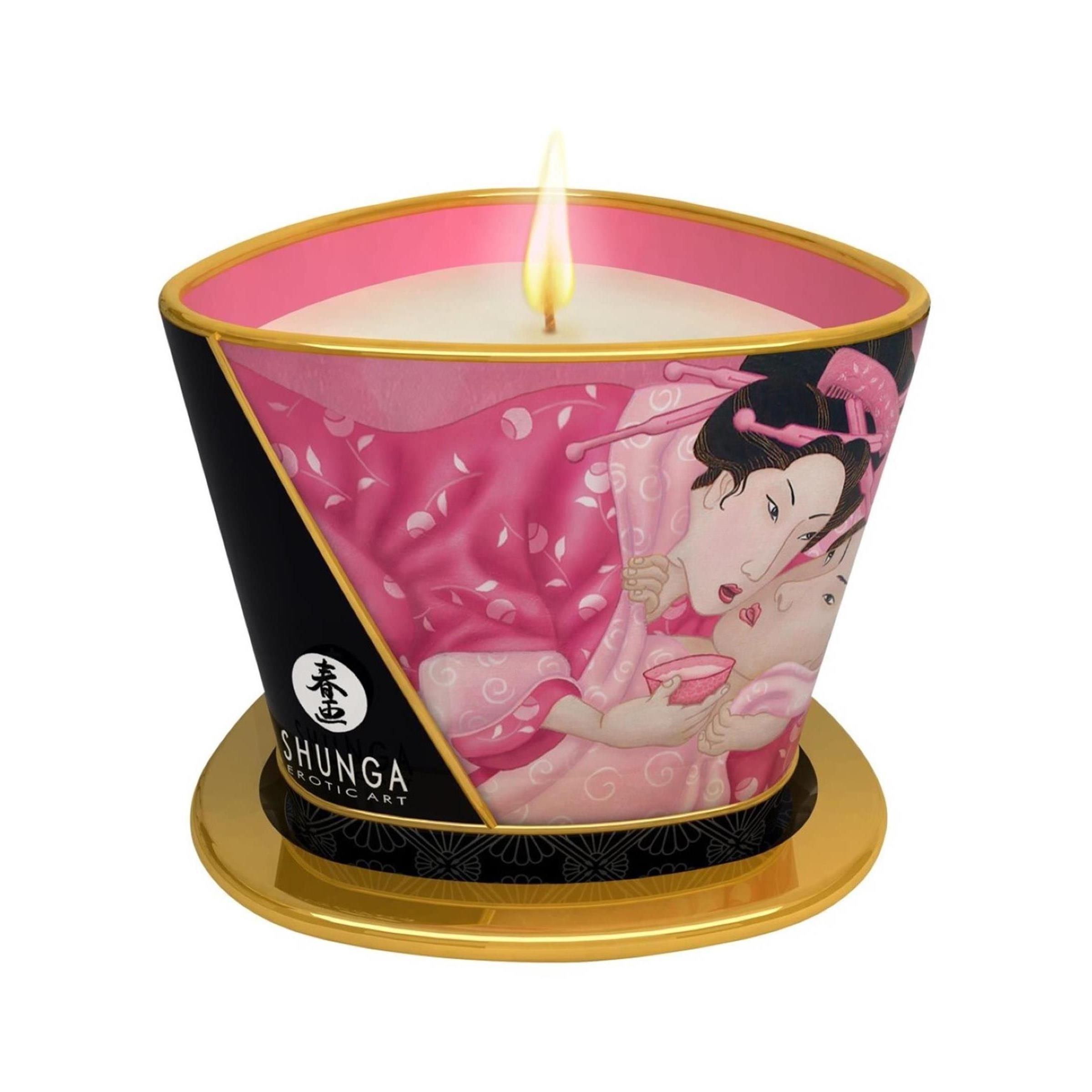 Brandende massagekaars met roze en zwarte versieringen die een Japans stel tonen. Op een gouden onderzetter.