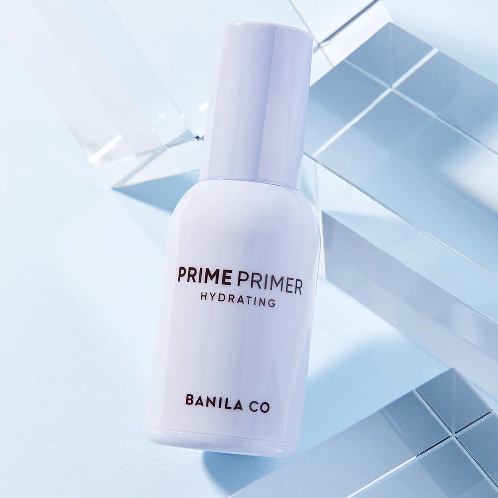 Witte fles met pomp. Opschrift: PRIME PRIMER HYDRATING, BANILA CO. Op blauwe achtergrond.