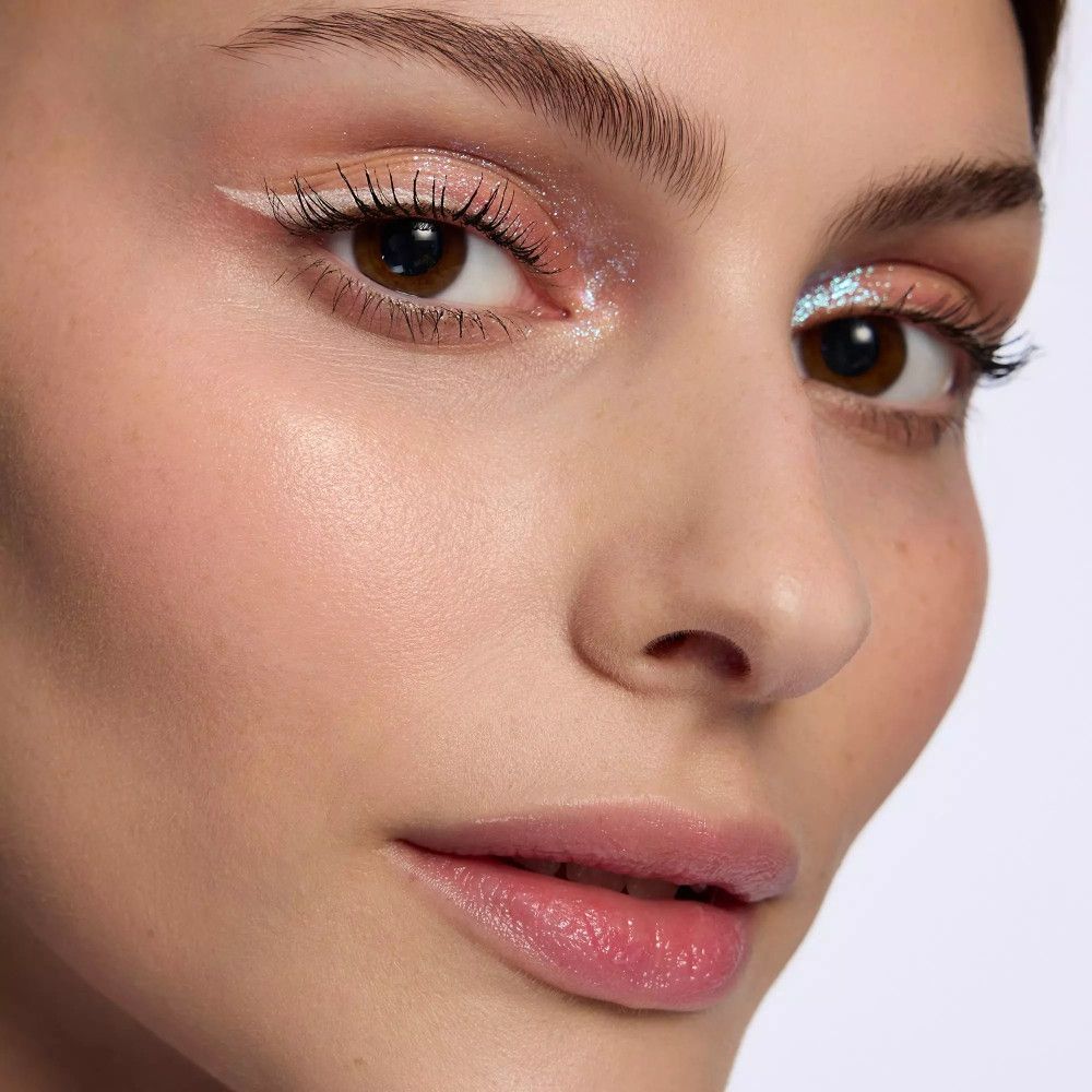 Gros plan sur un visage avec trait d'eyeliner blanc sur l'œil. Fard à paupières pailleté.
