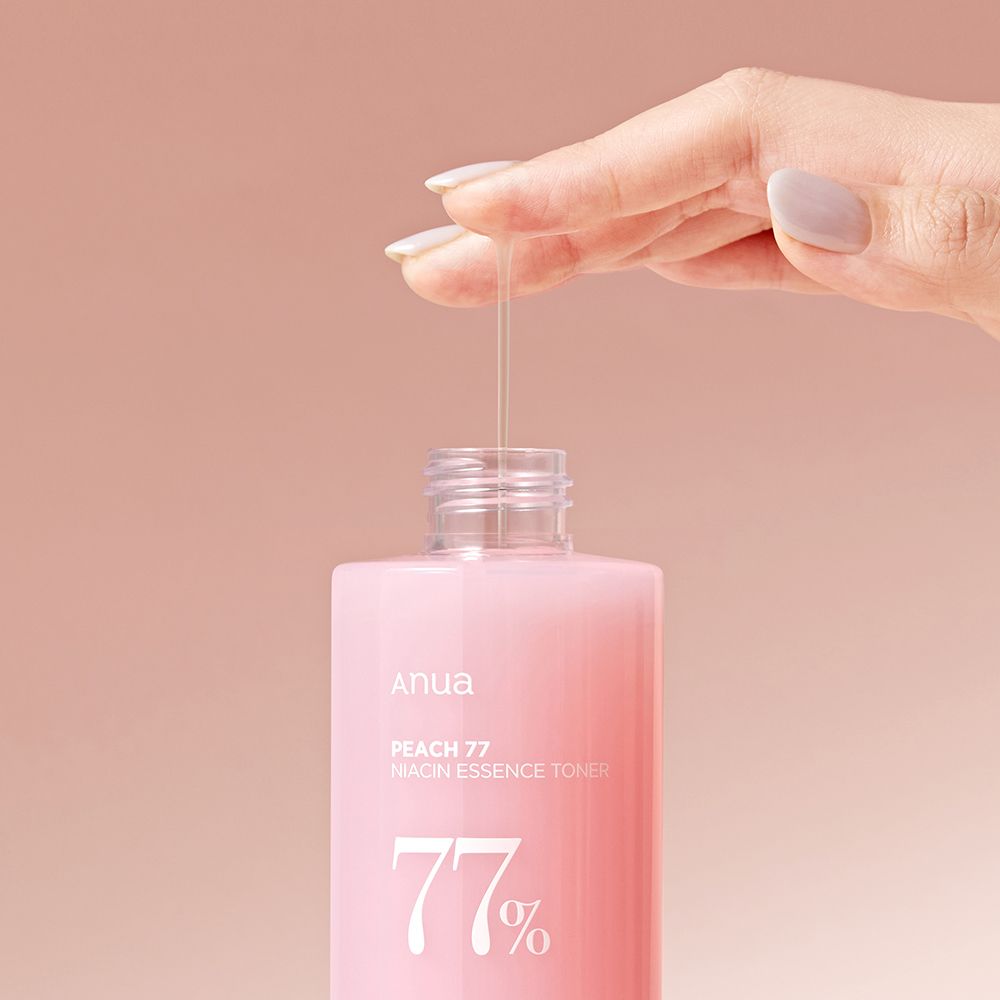 Une main verse du toner essence niacine ANUA Peach 77% d'une bouteille.