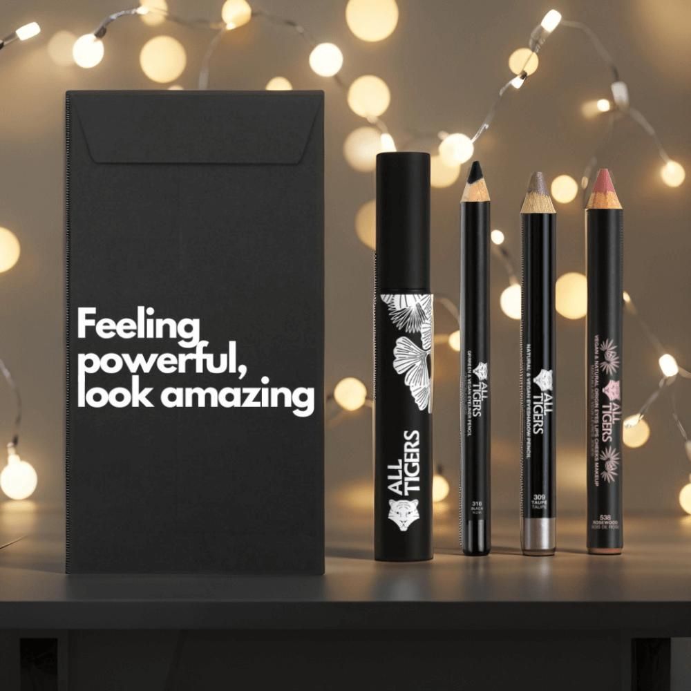 Zwarte geschenkverpakking met tekst. Daarnaast mascara, twee potloden en een lippenstift. Alle producten hebben het logo.
