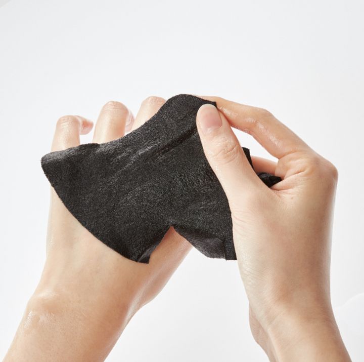 Handen houden een zwart gezichtsmasker vast. Het masker is gemaakt van zwart materiaal en is licht vochtig.